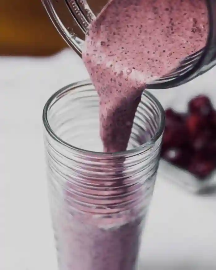 Pouring creamy chia seed smoothie into a tall glass