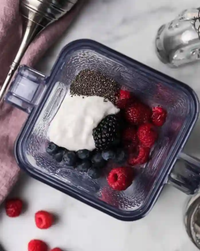 Fresh berries, chia seeds, and yogurt in a blender for chia seed smoothie